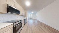 Located at 11 1st Ave in Bay Shore, NY, this thoughtfully designed 2-bedroom, 1-bathroom unit offers a clean, modern aesthetic across a single floor. Light wood-look flooring runs continuously throughout the space, complementing the bright white walls and creating a warm, cohesive feel.

The kitchen is outfitted with light wood cabinetry, a white subway tile backsplash, and a full suite of stainless steel appliances including a refrigerator, range with oven, built-in microwave, and dishwasher. It opens directly into a generous living area with a window that allows natural light to flow into the space.

The primary bedroom is spaciously sized, featuring a triple window arrangement that bathes the room in natural light, while the second bedroom also includes a window with exterior views and direct access to a closet. Both rooms offer comfortable proportions and a clean, neutral palette. A dedicated closet area provides additional storage.

The bathroom is finished with large-format white subway tile in the tub and shower surround, paired with a floating wood vanity and light tile flooring for a polished, contemporary look. A separate utility area houses a stacked washer and dryer alongside a water heater, adding everyday convenience to this well-appointed unit.