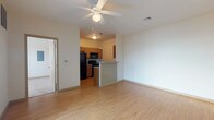 This single-story residence is designed with a practical, open-concept layout that connects the living area directly to the kitchen. The living space features light wood-style flooring and a ceiling fan with integrated lighting. A sliding glass door allows natural light to fill the room and provides outdoor views. The kitchen is positioned adjacent to the living area and is separated by a peninsula-style breakfast bar with beadboard detailing and a stone-look countertop. The kitchen itself is laid out in a galley configuration, equipped with medium-toned wood cabinetry, granite-style countertops, black appliances including a refrigerator, range, built-in microwave, and dishwasher, along with a pendant light fixture overhead.

The two bedrooms feature soft carpeting and large windows fitted with blinds that offer views of the surrounding area, providing ample natural light. The bathrooms include wood-style flooring, warm wood vanity cabinetry, and a full tub-shower combination. A dedicated laundry area houses a full-sized side-by-side washer and dryer with overhead wire shelving for additional storage. Neutral wall tones and consistent finishes create a cohesive, functional ambiance throughout the space.
