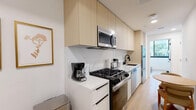 Located on Ohio Avenue in the Westwood neighborhood of Los Angeles, this modern 3-bedroom, 1-bathroom unit offers a thoughtfully designed single-floor layout. The interior features a clean, contemporary aesthetic with light hardwood flooring and crisp white walls throughout.

The combined kitchen and dining area is a standout space, showcasing flat-panel light wood cabinetry extending to the ceiling, a striking marble-look backsplash, and white quartz countertops. Stainless steel appliances include a gas range, over-the-range microwave, dishwasher, and refrigerator. A compact dining area with a round wooden table sits adjacent to the kitchen, alongside a wall-mounted mini-split system for climate control.

The bedrooms are bright and efficiently sized, each featuring light hardwood floors and wall-mounted mini-split units. The primary bedroom benefits from large black-framed windows that flood the room with natural light and offer open views of the tree-lined streetscape. Select bedrooms include sliding-door closets with built-in shelving.

The bathroom presents a modern, spa-like feel with terrazzo-style flooring, a floating wood vanity, oval mirror with matte black fixtures, and a walk-in shower. The unit also includes a dedicated laundry area and hallway for added convenience.