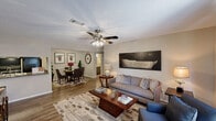 This single-floor, 2-bedroom, 2-bathroom home in Garden City, Georgia offers a functional and comfortable layout designed to maximize everyday living. The open-concept living and dining area features warm wood-style flooring, neutral-toned walls, and a ceiling fan with light fixture, creating a bright and inviting atmosphere. The living room flows seamlessly into the dedicated dining space, which is defined by a textured ceiling and connects directly to the kitchen. The galley-style kitchen is equipped with gray cabinetry, granite-look countertops, a double sink, and black appliances including a range and refrigerator, with a pass-through view into the dining area. The spacious primary bedroom features plush carpeting, a ceiling fan, a window with natural light, and a mirrored closet. The second bedroom is equally comfortable, with carpeted flooring, a ceiling fan, and natural light. Both bathrooms are finished with dark vanity cabinetry, granite-look countertops, large mirrors, wood-style tile flooring, and full tub-shower combinations. A dedicated laundry area accommodates a full-size side-by-side washer and dryer with overhead shelving for additional storage. Throughout the home, consistent finishes and neutral tones create a cohesive, move-in-ready aesthetic.