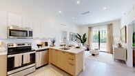 Located at 16395 Biscayne Blvd in North Miami Beach, this thoughtfully designed two-bedroom, two-bathroom residence offers a bright, open-concept layout with modern finishes throughout. The combined kitchen and living area serves as the heart of the home, featuring a sleek kitchen with stainless steel appliances, two-tone cabinetry in white and natural wood, white quartz countertops, and a peninsula with an undermount sink. The living area flows seamlessly toward floor-to-ceiling sliding glass doors that open to a spacious private terrace, furnished for outdoor lounging amid lush tropical landscaping. The primary bedroom is generously proportioned, with soft neutral tones and direct sightlines to the kitchen. The second bedroom offers a comfortable retreat with a large window framing lush greenery. Both bathrooms are finished with wood-tone vanities, white quartz surfaces, and marble-style tile surrounds in the tub and shower. A welcoming entryway with woven-panel cabinetry adds a refined touch, while two dedicated closets provide ample storage. Light tile flooring runs throughout, enhancing the airy, sun-filled ambiance of this well-appointed South Florida residence.