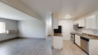 This single-floor unit offers a thoughtfully designed open-concept layout that seamlessly connects the living area and kitchen. Light-toned wood-look tile flooring runs throughout the space, creating a cohesive and easy-to-maintain interior. The expansive living area is bright and airy, featuring neutral gray walls and a window that frames views of surrounding greenery, allowing natural light to fill the room. A wall-mounted PTAC unit provides independent climate control.

The kitchen is well-appointed with crisp white cabinetry, dark granite-style countertops, and a full suite of stainless steel appliances including a gas range, built-in microwave, dishwasher, and refrigerator. A peninsula with a raised countertop visually separates the kitchen from the living space while maintaining an open feel. The kitchen also benefits from its own window, adding to the overall brightness.

The bedrooms are generously proportioned with the same neutral palette and wood-look flooring. One bedroom includes a walk-in closet with built-in shelving, offering practical storage. The bathroom features a full tub-and-shower combination with classic white subway tile surround. Overall, the space presents a clean, modern aesthetic with functional, well-maintained finishes throughout.