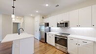 This thoughtfully designed 2-bedroom, 2-bathroom residence offers a cohesive and modern living environment across a single floor. The kitchen serves as a standout feature, showcasing crisp white shaker-style cabinetry, a large central island with a matte black faucet and sink, gleaming white countertops, a subway tile backsplash, and a full suite of stainless steel appliances including a French door refrigerator, range, and over-the-range microwave. Pendant lighting above the island adds a polished touch, while wood-look flooring flows through the kitchen and living area, providing warmth and continuity.

The living area is open and airy with recessed lighting and neutral wall tones that create a bright, inviting atmosphere. Both bedrooms feature plush carpeting, ceiling fans, and windows that allow natural light and outdoor views to filter in. Each bedroom benefits from dedicated closet space, with one walk-in closet offering built-in shelving and dual hanging rods for ample organization.

The bathrooms are finished with large-format light tile, soaking tub-shower combinations, and matte black fixtures that introduce a refined contrast. Clean lines and neutral palettes throughout the residence create a cohesive, contemporary aesthetic that is both functional and visually appealing.