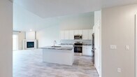 Located at 601 County U in Wrightstown, Wisconsin, this well-appointed single-floor unit offers a thoughtfully designed layout with one bedroom and one bathroom. The open-concept kitchen and living area serves as the heart of the home, featuring soaring ceilings that create an expansive, airy feel. The kitchen is outfitted with crisp white shaker cabinetry, granite countertops with elegant veining, a center island with an undermount sink, and a full suite of stainless steel appliances including a French door refrigerator, range, and microwave. Light wood-tone flooring flows throughout the entire unit, lending warmth and continuity to each room. The living area is anchored by a corner fireplace and benefits from generous natural light, with sliding glass doors opening to outdoor views of the surrounding greenery. A wall-mounted split system provides climate control alongside baseboard heating. The spacious primary bedroom features vaulted ceilings, a ceiling fan, a large window, and access to a dedicated closet. The bathroom includes white cabinetry, granite countertops, and tile flooring. Clean neutral tones and modern finishes throughout give this unit a fresh, move-in-ready appeal.