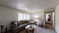 This single-floor residence offers a well-organized layout encompassing a living room, kitchen, dining area, two bedrooms, and a full bathroom. The living room serves as the central gathering space, featuring wall-to-wall carpeting, neutral-toned walls, and a textured ceiling. A large window fitted with vertical blinds allows natural light to fill the room, creating a bright and welcoming atmosphere.

The kitchen is functional and efficiently designed, featuring white cabinetry with ample storage, a tile backsplash, wood-style flooring, and white appliances including a gas range, refrigerator, and dishwasher. Adjacent to the kitchen, the dining area provides direct access to the unit's entry door and transitions between the wood-style flooring and carpet.

The primary bedroom is carpeted and comfortably sized, featuring a sliding-door closet. A second bedroom, also carpeted, includes a full sliding-door closet and provides flexibility for various sleeping arrangements. The bathroom features wood-style flooring, white tile surrounding the tub and shower combination, and a vanity with countertop storage. Throughout, the unit maintains a consistent, understated aesthetic with neutral walls and textured ceilings.