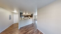 Located at 26031 72nd Ave NW in Snohomish, Washington, this single-floor home offers a well-organized layout designed for comfortable everyday living. The open-concept main area connects the living room and dining space, both finished with rich, dark wood-look flooring that extends throughout the common areas. Natural light flows in through multiple windows, offering views of the surrounding greenery.

The kitchen is a functional highlight, featuring dark cabinetry with ample storage, stainless steel appliances including a refrigerator, range, and dishwasher, and a clean white countertop. A peninsula counter separates the kitchen from the living space, providing a convenient breakfast bar area.

The bedrooms are carpeted for comfort and each includes a generously sized closet with panel doors. Windows in each bedroom invite natural light and outdoor views, contributing to a bright and airy feel throughout.

The home includes two bathrooms, each finished with wood-look flooring. Both feature elegant curved white vanities with chrome fixtures and large mirrors. One bathroom includes a tub and shower combination behind a curtain, while the other serves as a half or secondary bath.

Neutral wall tones and clean white trim create a cohesive, move-in-ready aesthetic throughout this well-maintained Snohomish home.