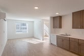 Located at 18730 Miner Ln in Morgan Hill, CA, this well-designed 2-bedroom, 1-bathroom residence offers a clean, modern aesthetic with light wood flooring and crisp white walls throughout. The open-concept living and kitchen area serves as the heart of the home, filled with natural light streaming through large windows fitted with blinds. The kitchen is thoughtfully equipped with warm-toned wood cabinetry, ample upper and lower storage, white appliances including a range, microwave, dishwasher, and refrigerator, and a functional countertop with an integrated sink. A wall-mounted mini-split unit in the living area ensures comfortable climate control year-round. Both bedrooms are bright and airy, benefiting from generous windows that invite natural light. The primary bedroom includes a closet with a built-in rod, while the second bedroom offers a clean, versatile layout. The full bathroom features warm wood cabinetry, a wide vanity with a large mirror, and accessibility-friendly grab bars. Light wood flooring flows consistently throughout all rooms, creating a cohesive and inviting atmosphere. A hallway and staircase access complete the functional layout of this well-appointed Morgan Hill residence.