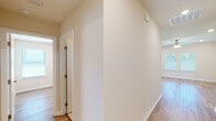 This single-story home presents a clean, modern layout designed for comfortable everyday living. The open-concept living and dining area flows seamlessly into the kitchen, where rich dark-stained cabinetry contrasts with granite-look countertops and stainless steel appliances, including a gas range, microwave, and refrigerator. Light wood-look flooring runs throughout the main living areas, complementing the neutral wall tones. A ceiling fan with integrated lighting anchors the living space, while multiple windows fitted with horizontal blinds allow natural light to fill the room.

A connecting hallway leads to the bedrooms, each finished with the same wood-look flooring and ceiling fans. The primary bedroom suite includes an en-suite bathroom featuring a tub/shower combination with built-in shelving, tile flooring, a granite-topped vanity, and direct access to a walk-in closet with built-in shelving. A second full bathroom mirrors this clean aesthetic with a tub/shower unit, granite vanity, and tile flooring.

The dedicated laundry room includes washer and dryer hookups, a dryer vent, and an overhead shelf for added storage. The attached two-car garage offers generous space, an automatic opener, and an electrical panel conveniently mounted on the wall.