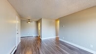 Located at 11501 Washington St in Northglenn, Colorado, this single-floor residence offers a well-organized layout designed for comfortable everyday living. The open living area is finished with durable hardwood-style flooring and neutral gray walls, creating a clean, modern aesthetic throughout. A ceiling fan provides additional comfort, while baseboard heating ensures warmth year-round. Sliding glass doors lead to a private balcony, filling the living space with natural light and offering pleasant outdoor views of the surrounding neighborhood and mature trees. The kitchen is efficiently designed with white cabinetry, light stone-finish countertops, and black appliances including a refrigerator and electric range, complemented by wood-style flooring that ties seamlessly into the main living area. The bedroom is carpeted for added comfort and features a natural light source via a window with vertical blinds. It is supported by two closets — one of which is a walk-in — providing generous storage. The bathroom includes a vanity with a stone-finish countertop, white cabinetry, a full tub-shower combination with white tile surround, and hardwood-style flooring. Textured ceilings are consistent throughout the unit, adding a classic residential character to the overall space.