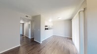 This single-floor residence offers a clean, functional layout with a cohesive neutral color palette and a variety of updated finishes throughout. The living area is spacious and open, featuring rich dark wood-look flooring, a textured ceiling, and a sliding glass door with vertical blinds that invites natural light and provides access to the outdoors. The space flows naturally into a pass-through kitchen, which is outfitted with crisp white shaker-style cabinetry, granite-look countertops, black appliances including a range and dishwasher, and a window above the sink for added brightness. Adjacent to the kitchen, a separate dining or utility area offers additional functionality. The bedrooms are generously sized, finished with plush carpeting, neutral gray walls, and windows that bring in natural light, creating a comfortable and restful atmosphere. The bathrooms are well-appointed, each featuring white cabinetry, granite countertops, undermount sinks with brushed nickel fixtures, and wood-look flooring. One bathroom includes a tub-shower combination with white tile surround. Throughout the residence, consistent finishes including textured ceilings, clean white trim, and neutral tones create a cohesive and move-in-ready environment.