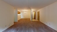 Located at 1 Court Blvd in Michigan City, Indiana, this single-floor residence offers a well-organized layout across a range of functional living spaces. The open living and dining area is finished with plush carpeting and features a classic chandelier as a central focal point, creating a warm and inviting atmosphere. A pass-through connects this area to the kitchen, which is designed in a galley style with warm oak cabinetry lining both sides, white countertops, a full-size refrigerator, and easy-to-maintain tile flooring — providing an efficient and practical cooking space. The bedrooms are generously sized, each carpeted and served by large windows that bring in ample natural light and offer views of the surrounding greenery. One bedroom includes a walk-in closet and direct access to an en suite bathroom, while another features a sliding glass door opening to the exterior. Two full bathrooms serve the residence: one equipped with a tub-shower combination and the other with a glass-enclosed shower stall. Both bathrooms include extended vanities with oak cabinetry, white countertops, and tile flooring. Throughout the space, warm wood-toned door frames and trim provide a cohesive and classic aesthetic.
