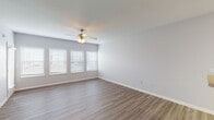 This single-floor residence offers a well-organized layout with a variety of functional spaces throughout. The living area is generously sized, featuring durable wood-look plank flooring and a ceiling fan with integrated lighting. A bank of windows fitted with white blinds allows natural light to fill the room, creating a bright and welcoming atmosphere.

The kitchen is positioned adjacent to the living area and features an open pass-through design with a breakfast bar counter. White cabinetry provides ample storage, while light-toned countertops complement the tile flooring. White appliances, including a refrigerator, electric range, and built-in microwave, are included.

The bedrooms are carpeted and each equipped with a ceiling fan with light fixture. One bedroom notably features a tray ceiling detail, adding architectural interest. A doorway from this room provides direct access to the bathroom, which includes a tub and shower combination with sliding glass doors, tile flooring, white cabinetry, and a vanity with a light-toned countertop. Throughout the unit, neutral gray walls and white trim provide a clean, cohesive aesthetic.