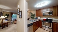 This single-floor residence offers a thoughtfully designed open-concept layout that seamlessly connects the kitchen, dining, and living areas. The kitchen is well-equipped with rich wood cabinetry, granite-style countertops, stainless steel appliances including a range, dishwasher, and microwave, along with a double-basin sink and light hardwood flooring. A half-wall peninsula separates the kitchen from the dining area, which features a ceiling fan and easy access to the living space.

The living room is warm and inviting, centered around a tiled fireplace with a classic mantel and complemented by plush carpeting. Natural light filters in through a large window overlooking a greenery-filled outdoor area. The bedroom is generously sized, featuring built-in closet organizers, carpet flooring, and windows with drape coverings that provide privacy and light control.

Two bathrooms serve the unit, each finished with matching wood vanities, granite-style countertops, tile flooring, and large mirrors. One bathroom includes a full soaking tub with a shower. An in-unit laundry area with bifold doors rounds out the practical features of this comfortable, cohesive living space.