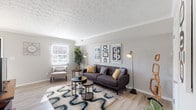 This two-floor home in Columbus, Ohio offers a well-organized layout designed for comfortable everyday living. The main level features a welcoming living room with light hardwood-style flooring, a textured ceiling, crown molding, and large windows that invite ample natural light. The space is open and versatile, with a staircase leading to the upper level. Adjacent to the living area is a cozy dining nook, brightened by a window with blinds and accented by hanging greenery. The kitchen is equipped with white cabinetry, granite-style countertops, a gas range, and black appliances, all complemented by light wood-style flooring. Upstairs, the home offers multiple bedrooms, each carpeted and featuring ceiling fans and windows that provide natural light. The primary bedroom includes a walk-in closet, while additional bedrooms offer generous space suitable for various needs. A full bathroom on the upper level features a tub-shower combination, a white vanity with storage, and hardwood-style flooring. Neutral gray tones carry throughout the home, creating a cohesive and calming aesthetic. The overall layout is practical and functional, making this Beechwold neighborhood home a solid choice for those seeking comfortable multi-level living in Columbus.