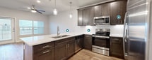 This 670 square foot apartment in Katy, TX offers a well-designed living space with one bedroom and two bathrooms. The open-concept layout maximizes the available area, seamlessly blending the kitchen, living, and dining spaces. The kitchen boasts dark wood cabinetry, stainless steel appliances, and a sleek white countertop with a breakfast bar, perfect for casual dining or entertaining.

The living area features warm wood-look flooring and large windows that flood the space with natural light. A sliding glass door leads to a small balcony, extending the living space outdoors. The bedroom, measuring 140 square feet, includes plush carpeting and a large window, creating a cozy retreat. A walk-in closet provides ample storage space.

Both bathrooms are well-appointed, with one showcasing modern tile flooring and a combination bathtub-shower. Throughout the apartment, ceiling fans and recessed lighting add both functionality and style. The neutral color palette allows for easy personalization, making this compact apartment an ideal canvas for various design preferences.
