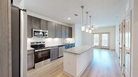 Located at 1200 Deer Moss Loop in Niceville, FL, this well-appointed one-bedroom, one-bathroom residence offers a thoughtfully designed single-level layout. Light-toned hardwood flooring runs throughout the main living areas, creating a clean and cohesive aesthetic.

The kitchen is a standout feature, showcasing rich dark-toned cabinetry, granite countertops, a classic white tile backsplash, and a full suite of stainless steel appliances including a refrigerator, range, microwave, and dishwasher. A central island with granite counters and stylish pendant lighting above provides additional prep space and a natural gathering point.

The open living area extends from the kitchen and is bathed in natural light, with French doors leading to a private balcony. A ceiling fan adds comfort to the space.

The bedroom offers plush carpeting, a ceiling fan, and a window with natural light, complemented by a dedicated closet for storage.

The bathroom is finished with dark wood cabinetry, a granite vanity top, a tiled tub-shower combination, and light hardwood flooring, maintaining the consistent modern style found throughout the home.