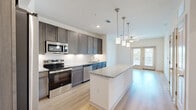 Located at 1200 Deer Moss Loop in Niceville, FL, this well-appointed one-bedroom, one-bathroom residence offers a thoughtfully designed single-level layout. Light-toned hardwood flooring runs throughout the main living areas, creating a clean and cohesive aesthetic.

The kitchen is a standout feature, showcasing rich dark-toned cabinetry, granite countertops, a classic white tile backsplash, and a full suite of stainless steel appliances including a refrigerator, range, microwave, and dishwasher. A central island with granite counters and stylish pendant lighting above provides additional prep space and a natural gathering point.

The open living area extends from the kitchen and is bathed in natural light, with French doors leading to a private balcony. A ceiling fan adds comfort to the space.

The bedroom offers plush carpeting, a ceiling fan, and a window with natural light, complemented by a dedicated closet for storage.

The bathroom is finished with dark wood cabinetry, a granite vanity top, a tiled tub-shower combination, and light hardwood flooring, maintaining the consistent modern style found throughout the home.