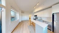 This contemporary 2-bedroom, 1-bathroom residence in Calgary, AB offers a thoughtfully designed open-concept layout with clean, modern finishes. Light hardwood flooring runs throughout, complementing the crisp white walls and creating a bright, cohesive aesthetic.

The combined living, dining, and kitchen area forms the heart of the home. The kitchen is outfitted with sleek white cabinetry reaching to the ceiling, a white subway tile backsplash, stainless steel appliances including a refrigerator, range, built-in microwave, and dishwasher, and a central island with a white countertop. Track lighting overhead and large windows allow abundant natural light to fill the space. A wall-mounted mini-split unit provides efficient climate control. A door from the living area leads directly to the private balcony, offering outdoor views of the surrounding neighbourhood.

Two well-proportioned bedrooms feature windows with neighbourhood views and baseboard heating. Sliding doors maximize usable space in the bedrooms and closet areas. The full bathroom includes a tiled tub-shower combination, toilet, and vanity. Two hallways connect the rooms efficiently, and a dedicated entrance provides a welcoming arrival. The layout is practical and well-suited for everyday living.