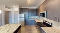 Located on Brickworks Drive in Cayce, South Carolina, this single-story residence showcases a contemporary design with thoughtfully selected finishes throughout. The open-concept kitchen serves as a central highlight, featuring a large granite-topped island with an undermount sink and pendant lighting overhead. Dark espresso cabinetry reaches toward the ceiling, providing generous storage, while a clean tile backsplash and a full suite of stainless steel appliances—including a range, built-in microwave, and refrigerator—complete the space. Track lighting adds a modern touch above.

The living area flows naturally from the kitchen, finished with light-toned wood-style flooring and a ceiling fan. French-style doors invite natural light and provide outdoor access, enhancing the open and airy feel of the room. Multiple bedrooms feature plush carpet flooring, ceiling fans, and windows that bring in natural light, offering comfortable and versatile spaces.

The bathrooms are well-appointed, each featuring granite countertops atop dark cabinetry, undermount sinks, and tub-shower combinations. Light wood-style flooring continues through the bathrooms, maintaining a cohesive aesthetic. A walk-in closet is accessible from one of the bathrooms, adding practical storage. Overall, the unit presents a clean, modern ambiance with consistent, quality finishes.