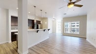 Located in the heart of San Diego at 450 Tenth Avenue, this well-appointed 2-bedroom, 3-bathroom residence offers a thoughtfully designed single-floor layout. Light wood-style flooring flows throughout, complementing the clean, modern aesthetic of the space.

The open-concept living area seamlessly connects the kitchen, dining, and living spaces. The kitchen is equipped with dark espresso cabinetry, stainless steel appliances including a full-size refrigerator, electric range, and microwave, all framed by light quartz countertops. A peninsula with bar seating and stylish pendant lighting serves as a natural focal point, while a ceiling fan and track lighting enhance the adjoining living area. Large windows and a private balcony with horizontal rail detailing offer views of the surrounding downtown San Diego skyline and streetscape.

Both bedrooms feature ceiling fans, wide windows, and hardwood-style flooring. The primary bedroom includes its own walk-in closet with built-in shelving and rod systems, alongside a dedicated en-suite bathroom. Three full bathrooms are finished with tile flooring, dark vanity cabinetry, white quartz counters, and full soaking tub-shower combinations. Additional storage is provided through four closets distributed across the unit, including walk-in options with multi-level hanging rods.