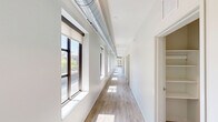 Located at 1107 S University Ave in the heart of Ann Arbor, this expansive 5-bedroom, 6-bathroom unit offers generous living space designed with a modern, urban aesthetic. The open-concept living room is bright and airy, featuring large floor-to-ceiling windows that flood the space with natural light and provide views of the surrounding cityscape. Exposed industrial-style ductwork adds a contemporary loft character, complemented by light wood-tone flooring and ceiling fans throughout. The well-appointed kitchen is a standout feature, centered around a large granite-topped island with bar seating, pendant lighting, stainless steel appliances, and rich dark wood cabinetry. Each of the five bedrooms offers a functional layout with carpeted flooring, individual windows, and access to one of six bathrooms. The bathrooms are consistently finished with warm wood vanities, granite countertops, light wood-look tile flooring, and walk-in glass shower enclosures. A spacious private terrace provides sweeping views of the surrounding Ann Arbor neighborhood and the University of Michigan campus. Two hallways connect the layout efficiently, making the overall flow practical for shared living. This unit combines modern finishes with industrial design elements in a prime location.