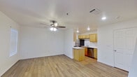 This two-story residence is efficiently designed across two equally sized floors, offering a well-organized layout that maximizes functionality. The main floor hosts the open-concept living room and kitchen, finished with light wood-look flooring throughout and a ceiling fan with light fixture. The kitchen is equipped with stainless steel appliances, including a refrigerator, electric range, and dishwasher, complemented by light wood cabinetry, white countertops, and a central island that provides additional workspace and storage. Tile flooring distinguishes the kitchen area. A bright entry area with a window allows natural light to filter in, enhancing the openness of the main floor. A carpeted staircase connects the two levels, leading to the upper floor where the generously proportioned primary bedroom is located. The bedroom features neutral carpet, a ceiling fan, a window with blinds for natural light and privacy, and access to a closet. The full bathroom includes a tiled tub-shower combination with brushed nickel fixtures and wood cabinetry. Throughout the space, white walls and clean finishes create a bright, neutral aesthetic.