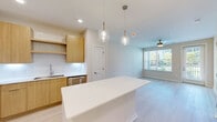 Located at 1224 Old Peachtree Rd NE in Lawrenceville, GA, this well-appointed 1-bedroom, 1-bathroom residence offers a thoughtfully designed open-concept layout with a clean, modern aesthetic throughout. Light wood-style flooring flows seamlessly across the entire space, complementing the neutral warm-beige palette on the walls.

The kitchen serves as a centerpiece of the home, featuring a large white quartz island illuminated by elegant glass pendant lights, warm wood cabinetry with open shelving, a white tile backsplash, and a full suite of stainless steel appliances including a refrigerator, range, microwave, and dishwasher. The kitchen opens naturally into the living room, which benefits from a ceiling fan and a generous window with outdoor views, as well as a glass door leading to a private outdoor area.

The bedroom is a comfortable, light-filled retreat with a ceiling fan, large windows offering views of the surrounding greenery, and ample natural light. A dedicated closet provides practical storage.

The bathroom showcases a long floating wood vanity with dual sinks, rectangular mirrors, stylish pendant lighting, and modern brushed nickel hardware, lending a spa-like quality to the space. The overall design is contemporary and move-in ready.