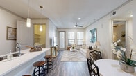 Located in Houston's vibrant midtown corridor, this 2-bedroom, 2-bathroom residence offers a well-considered single-floor layout that balances comfort and functionality. The open-concept living and dining area is bathed in natural light through multiple windows with adjustable blinds, complemented by wood-look flooring, a ceiling fan, and direct access to the outdoors. The kitchen is a standout feature, showcasing rich dark-wood cabinetry, a mosaic tile backsplash, stainless steel appliances, pendant lighting, and a white quartz island with bar seating — ideal for both cooking and casual dining. A dedicated dining nook with open shelving, mosaic tile accents, and hardwood flooring adds a stylish touch. The spacious primary bedroom includes a generous walk-in closet with ample hanging and shelving space. Both bedrooms feature plush carpeting and large windows that bring in natural light. The primary bathroom offers a dual-sink vanity with dark wood cabinetry, white countertops, a soaking tub, a separate shower with tile surround, and tile flooring. A dedicated laundry area houses a full-size side-by-side washer and dryer. Throughout, the residence maintains a clean, neutral palette with modern finishes and a warm, inviting ambiance.