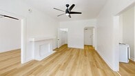 Located at 687 Shatto Place in Los Angeles, this efficiently designed 1-bedroom, 1-bathroom unit offers a thoughtful single-floor layout that maximizes every square foot. Light wood flooring flows consistently throughout the space, lending warmth and visual continuity from room to room.

The living room serves as the heart of the unit, highlighted by a charming decorative fireplace, a ceiling fan with built-in lighting, and a large window fitted with blinds that invite natural light while maintaining privacy. An arched entryway connects the living area to the hallway, adding a touch of classic character to the otherwise clean, modern aesthetic.

The bedroom continues the bright, airy feel with its own ceiling fan, a generously sized window, and direct access to a dedicated closet complete with a hanging rod — providing practical storage solutions. Crisp white walls throughout the unit create a neutral backdrop that enhances the sense of openness.

The kitchen is functional and well-equipped, featuring a gas range, white cabinetry, ample counter space, and a sink. The bathroom offers a full tiled tub and shower combination with a vanity and mirror. A dedicated laundry area adds everyday convenience. The entrance and hallway provide a smooth transition between all areas of the home, creating a cohesive and livable flow throughout.