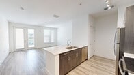 Located at 1659 2nd St in the heart of Sarasota, Florida, this well-appointed one-bedroom, one-bathroom unit offers a thoughtfully designed single-floor layout with a clean, modern aesthetic throughout. Light wood-look flooring runs continuously through the main living areas, complementing the crisp white walls and creating a bright, cohesive atmosphere.

The open-concept kitchen and living area forms the heart of the unit. The kitchen is equipped with stainless steel appliances — including a refrigerator, electric range, and over-the-range microwave — paired with two-tone cabinetry featuring white upper cabinets and dark wood-grain lower cabinets. White quartz countertops and a tile backsplash add a polished touch, while track lighting overhead ensures excellent illumination. A peninsula with an undermount sink provides additional prep space and defines the kitchen from the living area.

The bedroom is comfortably sized, filled with natural light from a window with blinds, and features direct access to a dedicated walk-in closet outfitted with wire shelving for ample storage. The bathroom includes a marble-style vanity countertop, white cabinetry, a large mirror, and a glass-enclosed walk-in shower, all set on earthy tile flooring. A hallway connects the spaces, completing this efficient and stylish Sarasota residence.