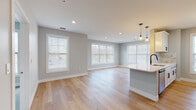 Located at 400 Blake St in New Haven, CT, this thoughtfully designed single-floor residence offers a seamless blend of modern finishes and functional layout. The open-concept living and kitchen area is anchored by light-toned hardwood flooring, soft neutral gray walls, and abundant natural light streaming through multiple large windows. The kitchen features a central island with a white quartz countertop, pendant lighting, white shaker-style cabinetry with matte black hardware, stainless steel appliances, and a striking marble-style tile backsplash. Recessed lighting throughout the living area enhances the bright, airy atmosphere. A hallway connects the living spaces to the private quarters, where multiple bedrooms are finished with plush blue-gray carpeting and generously sized windows that frame outdoor views of the surrounding neighborhood. The bathrooms are appointed with large-format stone-look floor and wall tile, a soaking tub with a tiled surround, a shower fixture, and brushed nickel hardware accents. Clean white trim and consistent neutral tones throughout the unit create a cohesive, contemporary aesthetic well-suited for comfortable everyday living.
