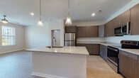 This single-floor residence in Charlotte, NC offers a thoughtfully designed layout with modern finishes and an open, airy feel. The centerpiece of the home is a well-appointed kitchen featuring rich dark wood cabinetry, granite countertops, a large central island with an integrated sink, and stainless steel appliances including a refrigerator, range, and over-the-range microwave. Pendant lighting with gold accents hangs above the island, adding a stylish touch. Light wood-look flooring runs throughout the main living and kitchen areas, contributing to a bright and cohesive aesthetic.

The bedrooms are comfortably sized, featuring plush wall-to-wall carpeting, ceiling fans, and windows that allow ample natural light. One bedroom offers a direct outdoor view of the surrounding community.

The bathrooms are clean and functional, with a tub-shower combination finished in crisp white tile, wood-toned vanity cabinetry, granite countertops, and wood-look flooring that complements the rest of the home. Recessed lighting and neutral wall tones throughout the space create a calm, move-in ready environment. The overall design balances contemporary style with practical living, making this Charlotte residence a comfortable and attractive home.