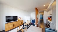 Located at 455 East Waterside Drive in Chicago's vibrant Lakeshore East neighborhood, this one-bedroom, one-bathroom residence offers a well-designed layout that maximizes every square foot of its compact footprint. Dark hardwood floors run throughout, creating a cohesive and polished aesthetic from the entry hallway to the living area.

The living room is the centerpiece of the space, anchored by expansive floor-to-ceiling windows that flood the room with natural light and frame sweeping views of the Chicago skyline and Lake Michigan beyond. A clean, contemporary design is carried throughout, with crisp white walls accented by a warm terracotta feature wall that adds depth and character.

The kitchen is integrated efficiently alongside the living area, offering modern cabinetry and a functional layout. A dedicated in-unit laundry area and two closets provide practical storage solutions throughout the residence.

The bedroom is a quiet, well-proportioned retreat featuring a built-in closet and a warm wood-paneled headboard wall, maintaining the unit's modern yet inviting tone. The bathroom is finished with a floating wood-grain vanity, a large mirror with integrated lighting, and a glass-enclosed shower, reflecting a clean and contemporary design sensibility throughout.