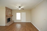 This single-story residence offers a thoughtful layout with a blend of practical features and comfortable living spaces. The open living and dining area serves as the heart of the home, highlighted by rich hardwood-style flooring, crown molding, and a striking full-height brick fireplace with a wood mantel as its centerpiece. Natural light filters through multiple windows fitted with blinds, while a ceiling fan with a light fixture adds comfort overhead. A chandelier pendant anchors the dining area, which also features a convenient built-in counter ledge. The front entry door includes a transom window, brightening the foyer.

The galley-style kitchen is efficiently designed with white cabinetry, dark granite-look countertops, and white appliances including a range, microwave, and dishwasher. A pass-through counter connects the kitchen to the main living area. Directly off the kitchen, a dedicated laundry room houses a full-size washer and dryer. The bedroom features plush carpet flooring, a ceiling fan, and a window for natural light. Two bathrooms are present—one with a tub-shower combo and tile flooring, and another with a vanity and tile flooring. Throughout, neutral tones create a clean, cohesive atmosphere.