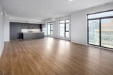 Located on the 11th floor at 66 Weber St E in downtown Kitchener, this three-bedroom, four-bathroom unit delivers a well-designed layout with modern finishes across a generously sized single floor. Light-toned hardwood flooring flows throughout the main living areas, complementing the clean white walls and contemporary aesthetic.

The open-concept living room is a standout space, featuring floor-to-ceiling windows with black frames on multiple walls and a sliding glass door leading to a private balcony, offering sweeping views of the Kitchener skyline. Natural light fills the space throughout the day.

The kitchen features tall, wood-grain cabinetry extending to the ceiling, a central island, white quartz countertops, and stainless steel appliances including a built-in microwave, stove, and refrigerator. A hallway connects the three bedrooms, each finished with hardwood flooring. Several bedrooms include sliding balcony access and dedicated closets. The four bathrooms feature dark wood vanities, marble-style quartz countertops, large mirrors, and tiled tub-shower combinations. A dedicated laundry room houses a stacked Whirlpool washer and dryer alongside a utility sink.