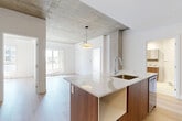 Located at 4845 Ch De La Côte-Saint-Luc in Montréal, this well-appointed 2-bedroom, 1-bathroom unit blends contemporary design with industrial-inspired elements across a single floor. The open-concept kitchen and living area serves as the heart of the space, anchored by a striking kitchen island clad in warm wood tones and topped with a light stone countertop. The kitchen is equipped with stainless steel appliances, integrated cabinetry, and a stylish backsplash, all complemented by light hardwood flooring that flows throughout. Exposed concrete columns and ceiling sections add an industrial character that contrasts beautifully with the crisp white walls. The living area benefits from natural light and access to outdoor views. Both bedrooms are bright and functional, featuring the same hardwood flooring, white walls, and concrete accents. The primary bedroom includes a wall-mounted air conditioning unit. The bathroom is finished in a clean, minimalist style with a soaking tub, toilet, and a wooden vanity topped with a white basin, all set against light terrazzo-style flooring. A dedicated closet provides additional storage, completing this thoughtfully designed urban residence.