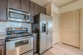 This contemporary apartment, located at 7727 Potranco Road in San Antonio, offers 910 square feet of well-designed living space. The single-story layout includes two bedrooms, two full bathrooms, and an open-concept kitchen and living area. The kitchen showcases dark wood cabinetry, stainless steel appliances, and granite countertops, complemented by pendant lighting and a breakfast bar. Durable wood-look flooring extends throughout the main living areas, while plush carpeting adds comfort to the bedrooms. Both bedrooms feature ceiling fans and large windows, allowing for ample natural light. The bathrooms are equipped with modern fixtures, including glass-enclosed showers and granite vanity tops. A dedicated laundry room with full-sized washer and dryer adds convenience. The primary bedroom, measuring 150 square feet, offers a spacious retreat. Throughout the apartment, neutral tones and clean lines create a fresh, contemporary ambiance. Additional features include track lighting in the kitchen and ample closet space, making this apartment both stylish and functional for modern living.