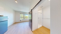 Located at 4612 Stone Way N in Seattle's vibrant Wallingford neighborhood, this efficiently designed studio unit makes smart use of every square foot across a single floor. Light-toned hardwood-style flooring runs throughout, lending a clean and cohesive feel to the entire space.

The open living area is anchored by a large picture window that frames lush, tree-lined views and floods the room with abundant natural light. The crisp white walls and recessed lighting further enhance the bright, airy atmosphere.

The kitchen is thoughtfully outfitted with glossy white cabinetry extending to the ceiling, a stainless steel refrigerator, built-in microwave, a cooktop, and a single-basin sink — all arranged along a single streamlined wall. An in-unit washer and dishwasher are seamlessly integrated into the kitchen layout, adding convenience without sacrificing the clean aesthetic.

A standout architectural detail is the sliding barn-style door with a frosted glass panel and matte black hardware, which provides a stylish and space-saving entry to the bathroom. The bathroom features a walk-in shower, a white vanity, and crisp white walls, maintaining the minimalist design language found throughout the unit.

Overall, this studio presents a modern, functional living space well-suited for those seeking an efficient and well-appointed home in Seattle.