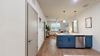 Located at 404 Harvey Mitchell Pkwy in College Station, this thoughtfully designed 2-bedroom, 2-bathroom residence offers a contemporary open-concept layout with cohesive modern finishes throughout. Wood-look flooring flows seamlessly across the entire unit, connecting each space with warmth and consistency.

The kitchen serves as a central focal point, showcasing bold navy cabinetry, a large island with a white countertop and bar seating, stainless steel appliances, and stylish globe pendant lighting. The adjacent living room benefits from a large window that invites natural light and features a ceiling fan overhead.

Each bedroom is a private, comfortable retreat with its own natural light from dedicated windows. Both bedrooms connect directly to their own private bathrooms, which are outfitted with matching navy vanities, white countertops, tiled shower stalls with curtains, and ceiling fans. The unit includes three closets, one of which is a spacious walk-in with wrap-around shelving and hanging rods, providing generous storage.

The clean, neutral color palette of white walls combined with navy accents creates a modern, cohesive aesthetic throughout the unit, making it a functional and stylish living space well-suited for residents in the College Station area.