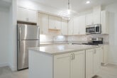 This single-floor residence at 11982 Seven Pine Dr in Holland, Michigan presents a clean, modern aesthetic throughout its thoughtfully designed layout. The open-concept kitchen serves as a central highlight, featuring white shaker-style cabinetry, a classic subway tile backsplash, stainless steel appliances, and a large center island topped with a light quartz countertop. Glass pendant lighting hangs above the island, complementing the recessed lighting overhead. Light-toned luxury vinyl plank flooring extends through the kitchen and living areas, creating a seamless, bright atmosphere.

The bedrooms are carpeted and well-proportioned, each equipped with ceiling fans and windows that allow natural light to filter in. At least one bedroom includes access to a walk-in closet with built-in shelving. The bathrooms are finished in a consistent neutral palette, with one featuring a tub-shower combination and another offering a white vanity with ample drawer storage and a well-lit mirror.

A dedicated laundry room houses a full-size washer and dryer alongside a water heater, adding practical convenience. Throughout the unit, white walls, light flooring, and understated hardware contribute to a cohesive, contemporary feel.
