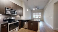 Located at 4100 Greenbriar Dr in Houston, TX 77098, this one-bedroom, one-bathroom residence offers a well-designed single-floor layout. The open-concept living, dining, and kitchen area serves as the heart of the home, featuring rich hardwood flooring, pendant lighting, and a ceiling fan overhead. The kitchen is outfitted with dark cabinetry, a tile backsplash, dark countertops, and a full suite of stainless steel appliances including a refrigerator, range, microwave, and dishwasher. A peninsula with a built-in sink provides additional prep space and separates the kitchen from the living and dining area, which is brightened by a window overlooking the exterior. The bedroom offers comfortable carpet flooring, neutral walls, and a window with outdoor views of the surrounding community. Three closets provide generous storage throughout the unit, supplemented by a dedicated laundry area and a hallway connecting the spaces. The bathroom features tile flooring, a tub-shower combination with white tile surround, and a wall-mounted cabinet for additional storage. The overall aesthetic is clean and contemporary, with a neutral color palette and modern finishes that create a cohesive, functional living environment.