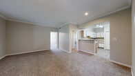 Located in Taylor, TX, this single-story home offers a practical and well-organized layout across two bedrooms, one bathroom, and an attached garage. The open-concept living room and kitchen area serves as the heart of the home, featuring neutral-toned carpet, crown molding, and recessed lighting that create a clean, welcoming atmosphere. A front entry door with sidelights and an adjacent window allows natural light to fill the living space, which also provides a clear view of mature trees outside.

The kitchen is efficiently designed with white cabinetry accented by light wood trim, granite-look countertops, and wood-look tile flooring. It includes a full suite of white appliances — an electric range, built-in microwave, and dishwasher — alongside a stainless steel sink, making it both functional and cohesive in style.

The primary bedroom features a ceiling fan, a window with outdoor views, and a closet, while the second bedroom offers carpeted flooring and ample wall space. The full bathroom includes a tub/shower combination, a vanity with granite-look countertops and wood-trimmed cabinetry, and wood-look tile flooring. A hallway connects the bedrooms and bathroom efficiently. The attached single-car garage provides additional storage and parking convenience.