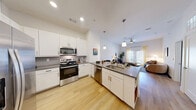 Located at 3901 E Parmer Ln in Manor, TX, this thoughtfully designed one-bedroom, two-bathroom residence offers a clean, modern aesthetic with an efficient and functional layout. Light wood-style flooring flows throughout the main living areas, complementing the bright white walls and creating a cohesive, contemporary feel.

The open-concept kitchen and living area serves as the heart of the home. The kitchen is equipped with stainless steel appliances — including a French door refrigerator, range, and microwave — white shaker cabinetry, a subway tile backsplash, and a large island with a quartz-style countertop and pendant lighting overhead, providing ample seating and prep space. The living room receives natural light through large windows dressed with sheer curtains, offering a warm and inviting atmosphere.

The bedroom is a comfortable retreat featuring a window with blinds and drapes, and direct access to the en-suite bathroom. The primary bathroom features a wide vanity with a gray countertop, white cabinetry, and large-format tile flooring. A spacious walk-in closet with wire shelving provides generous storage. A stacked washer and dryer unit is conveniently tucked within a dedicated laundry nook. A second full bathroom serves guests and additional needs.