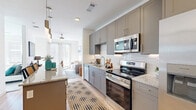 This thoughtfully designed 1-bedroom, 2-bathroom residence makes excellent use of its single-floor layout, delivering a modern and cohesive living experience. The open-concept kitchen and living area serves as the heart of the home, featuring light hardwood flooring, white walls, and abundant natural light from large windows at the far end of the living space. A ceiling fan adds comfort to the airy living room.

The kitchen is outfitted with sleek gray shaker-style cabinetry, granite countertops, a white geometric tile backsplash, and a full suite of stainless steel appliances including a range, microwave, dishwasher, and side-by-side refrigerator. A kitchen island with pendant lighting provides additional prep and dining space, seamlessly connecting the kitchen to the living area.

The primary bedroom is a comfortable retreat with access to a well-appointed en-suite bathroom featuring gray cabinetry, granite countertops, and a walk-in closet with built-in shelving. The second bathroom includes a soaking tub with elegant marble-style tile surround and brushed nickel fixtures. Additional functional spaces include a dedicated laundry room, utility room, and a second closet, rounding out the practical and polished layout of this residence.