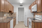Located at 431 SE 13th Ct in Deerfield Beach, Florida, this well-appointed 2-bedroom, 2-bathroom unit offers a comfortable and functional layout across a single floor. The galley-style kitchen is a standout feature, showcasing warm-toned wood cabinetry with detailed raised-panel doors, dark granite-style countertops, a tile backsplash, a stainless steel sink, and white appliances including a refrigerator, oven, and dishwasher. Light ceramic tile flooring runs throughout the kitchen, keeping the space bright and easy to maintain. The living room and bedrooms feature light wood-style plank flooring and ceiling fans, creating a cohesive and airy feel throughout. Both bedrooms are well-sized, with the primary bedroom offering generous proportions. The secondary bedroom includes a double sliding louvered closet for ample storage. The two bathrooms are finished in clean white tiling, with one featuring a tub-shower combination and the other a walk-in shower. A private balcony off the living area provides serene views of lush green lawns, swaying palm trees, and a community pool, capturing the relaxed Florida lifestyle. The unit's clean, neutral palette and practical layout make it a versatile and inviting space.