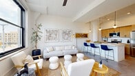 Located at 5000 Euclid Ave in Cleveland's vibrant Midtown neighborhood, this one-bedroom, one-bathroom residence offers a thoughtfully designed layout filled with natural light. The open-concept living and dining area is anchored by soaring ceilings with exposed beam detailing, a ceiling fan, and large black-framed windows that frame city views and flood the space with daylight. The kitchen features light wood cabinetry, white countertops, stainless steel appliances including a refrigerator, electric range, built-in microwave, and dishwasher, alongside a peninsula with pendant lighting and bar seating that connects seamlessly to the dining area. The bedroom is a serene retreat with arched architectural detailing, dual windows offering neighborhood views, and access to generous closet storage. Two closets provide ample organization throughout the unit. The bathroom is well-appointed with a wood vanity, white countertop, walk-in tiled shower with dark hardware accents, and neutral tile flooring. An in-unit laundry area adds everyday convenience. Throughout, polished concrete-style flooring and a crisp white palette create a cohesive, modern aesthetic that feels both airy and inviting.