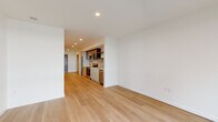 Located at 23 North Broadway Street in Tacoma, WA, this thoughtfully designed one-bedroom, one-bathroom unit offers a clean, contemporary aesthetic throughout. Light-toned hardwood flooring flows seamlessly across the entire space, complementing the crisp white walls and recessed lighting that brighten every room.

The open-concept layout connects the living area to a well-appointed galley-style kitchen featuring stainless steel appliances, including a refrigerator, range, microwave, and dishwasher. Dark wood upper cabinetry and open shelving contrast neatly with white lower cabinets and a light stone countertop, while a tile backsplash adds a refined finish.

The living area is a standout, anchored by expansive floor-to-ceiling windows that frame sweeping views of the Puget Sound and surrounding cityscape, flooding the room with natural light. The bedroom continues this connection to the outdoors with large windows offering similar scenic water views, and includes access to a dedicated walk-in closet with built-in shelving. A second closet with sliding doors is conveniently located near the kitchen entrance.

The bathroom is finished in a clean, minimalist style with a white vanity, integrated sink, a tub-shower combination, and wood-look tile flooring. A hallway connects all rooms efficiently, enhancing the unit's practical and functional flow.