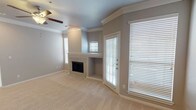 This single-floor residence offers a thoughtfully designed layout with a comfortable blend of functionality and style. The living area serves as the focal point of the home, highlighted by a marble-surround fireplace flanked by built-in shelving and a direct-access exterior door. Crown molding lines the walls, and a ceiling fan complements the vaulted ceiling, while multiple windows fitted with horizontal blinds allow natural light to fill the space. Soft, neutral-toned carpet extends throughout the living areas and bedrooms.

The kitchen is well-equipped with rich, dark wood cabinetry, light granite countertops, and a full suite of stainless steel appliances including a refrigerator, range, microwave, and double-basin sink. Wood-style flooring grounds the kitchen and flows into the adjacent spaces, connected to the living area through a graceful arched passageway.

The bedrooms are generously sized, each featuring ceiling fans and windows that bring in natural light. The bathrooms are finished with granite-topped vanities, dark wood cabinetry, and white tile tub-shower combinations, offering a clean and polished aesthetic. Overall, the space presents a cohesive, neutral palette with quality finishes throughout.