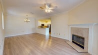 Located in Jacksonville, FL (32256), this single-floor residence offers a thoughtfully designed layout with a blend of light hardwood flooring and plush carpeting throughout. The spacious living and dining area is a central highlight, featuring crown molding, wainscoting, a ceiling fan with light fixture, an elegant chandelier, and a tile-surround fireplace. A breakfast bar connects the living area to the kitchen, which is outfitted with white cabinetry, light stone countertops, and a full suite of stainless steel appliances including a refrigerator, range, over-the-range microwave, and dishwasher. The bedrooms are generously sized; the primary bedroom features a tray ceiling with a ceiling fan, a walk-in closet with wire shelving, and an en-suite bathroom complete with a glass-enclosed shower, vanity with stone countertops, and hardwood flooring. Additional rooms feature large windows that invite natural light and views of the surrounding greenery. The home also includes a carpeted staircase, additional closet storage with built-in shelving, and a bright entry area with glass-paneled French doors. Crown molding and ceiling fans are present throughout, contributing to a cohesive and comfortable interior aesthetic.
