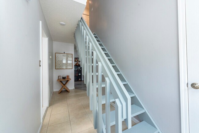Bright, open staircase with solid railings leading to your private upper living spaces. - 405 Windswept Dr